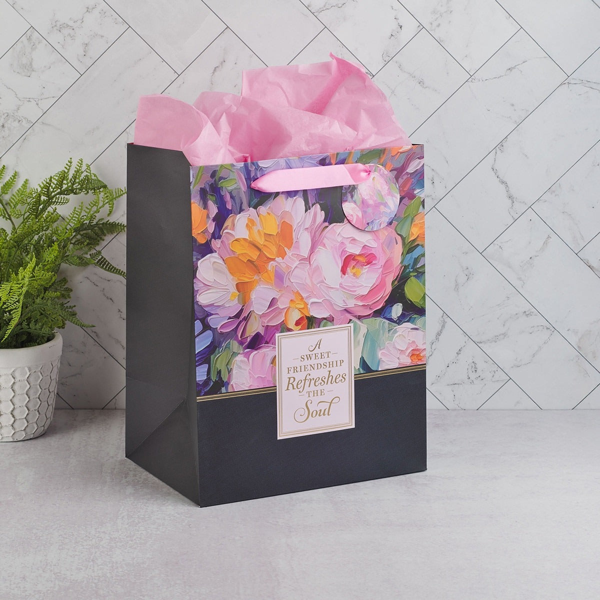 Large portrait gift bag with vibrant watercolor garden flowers, pink tissue paper, and sweet friendship sentiment on black background