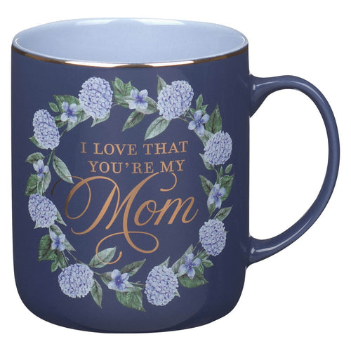 Blue ceramic coffee mug with floral wreath and gold script reading I love that you’re my Mom