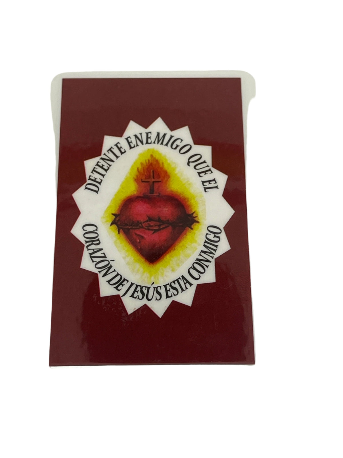 Laminated holy card with Sacred Heart of Jesus image and "Detente Enemigo" prayer in Spanish text around heart.