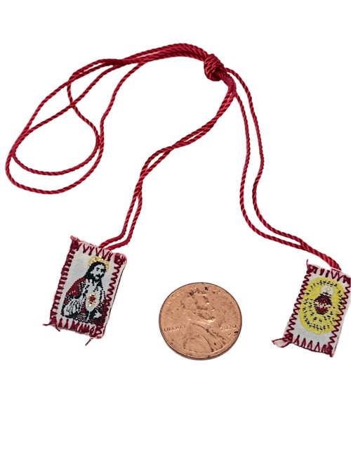 Small Detente red scapular with Sacred Heart of Jesus shield badges, 3/4" size shown next to penny for scale