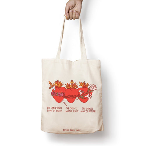Cotton canvas tote bag with red Sacred Hearts of Mary, Jesus, and Joseph illustration and text on white background