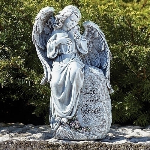 12" seated angel statue with wings and "Let Love Grow" inscription, placed outdoors with greenery background
