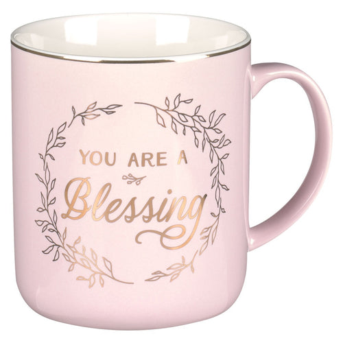 Pink ceramic coffee mug with gold “You Are A Blessing” text and decorative leaf wreath design