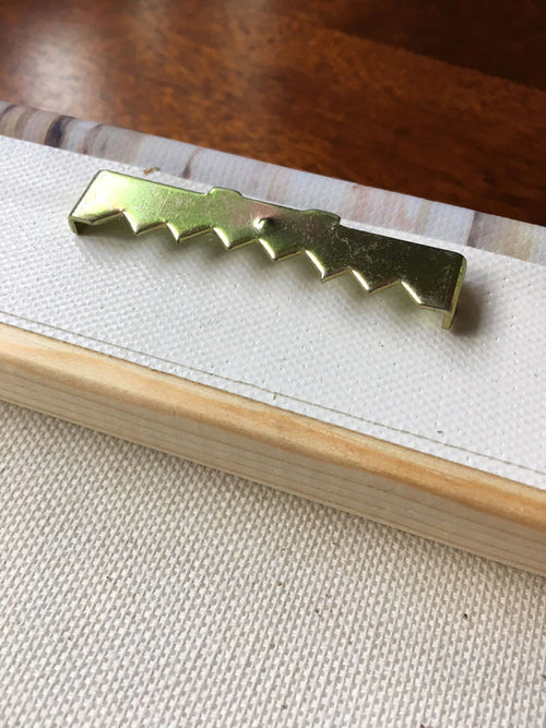 Close-up of gold sawtooth hanger attached to wooden frame of 10x14 inch canvas wall art.